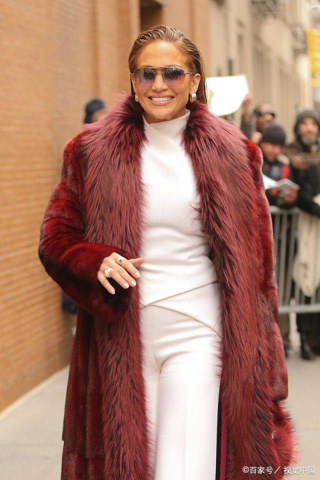 女星洛佩兹身穿一件枣红色皮草大衣,搭配阔腿裙裤